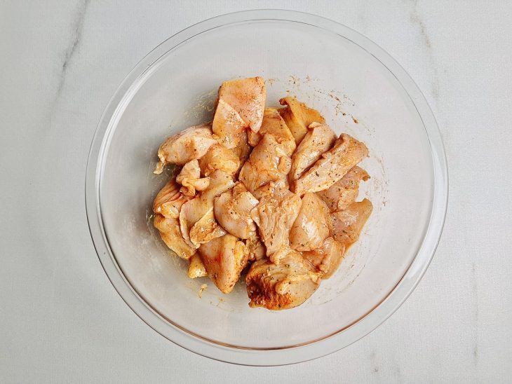 Frango temperado em uma tigela de vidro.
