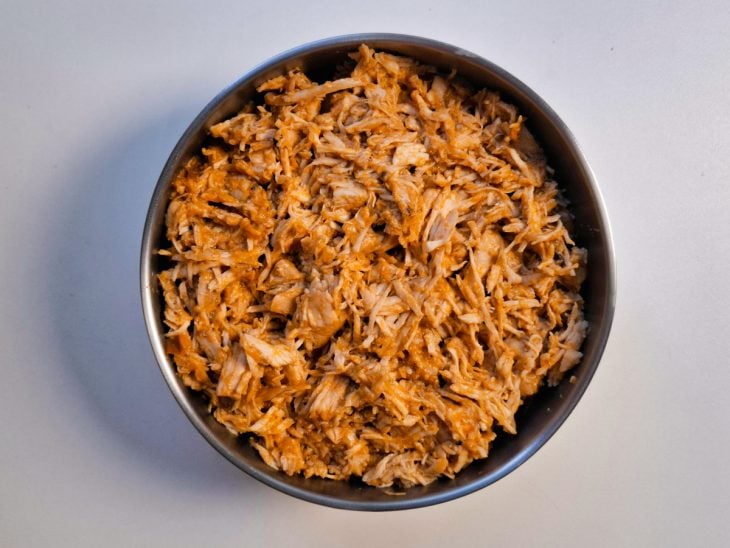 Frango desfiado com auxílio de garfos.