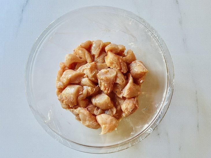 Frango temperado em uma tigela redonda de vidro.