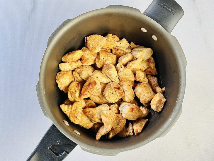 Frango dourado no azeite em uma panela.