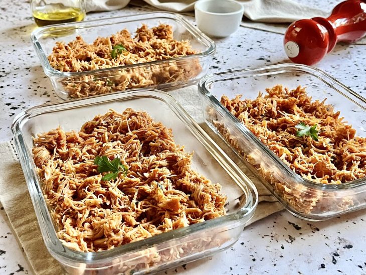 Frango desfiado simples dividido em recipientes de vidro.