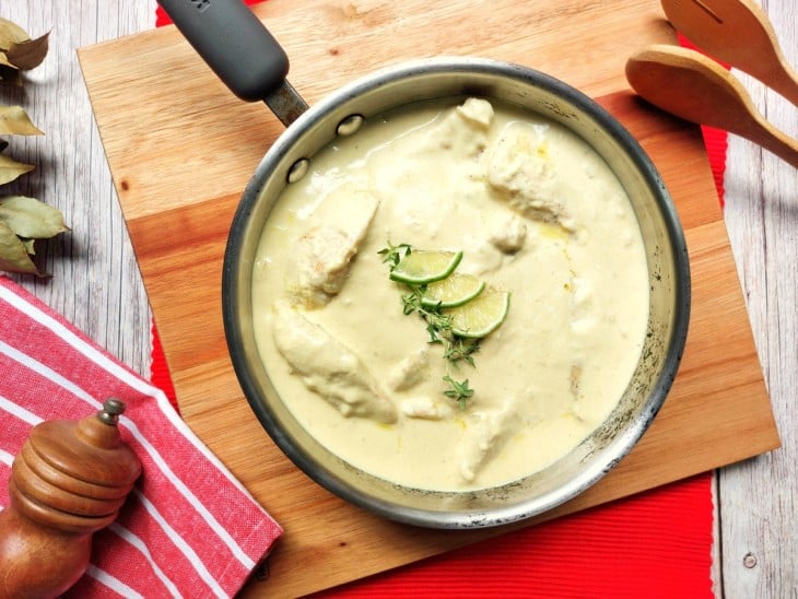 Frango Dijon servido em uma frigideira com rodelas de limão por cima.