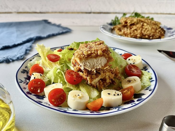 Filé cortado ao meio, servido em prato com salada de acompanhamento.