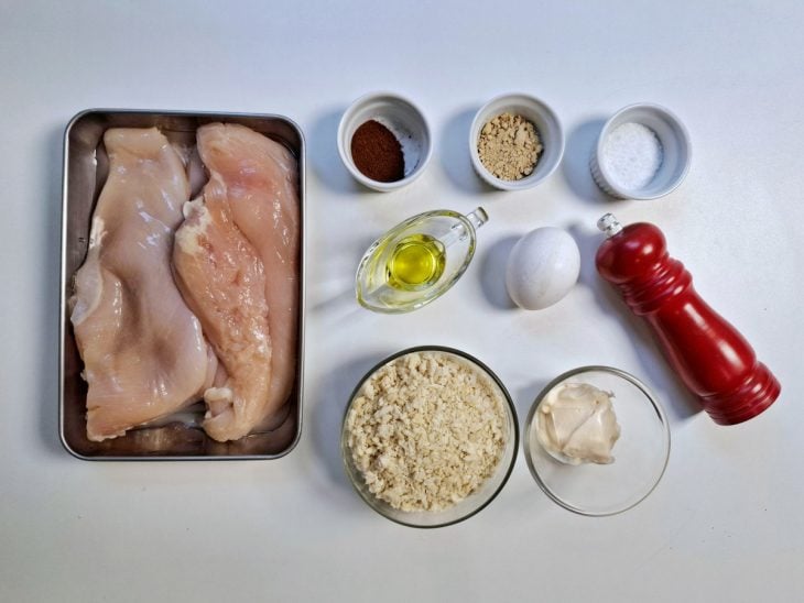 Ingredientes para a receita de frango empanado reunidos em uma bancada.