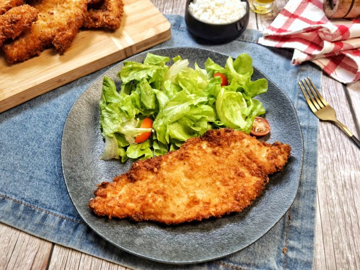 Frango empanado simples servido com salada, pronto para consumo.