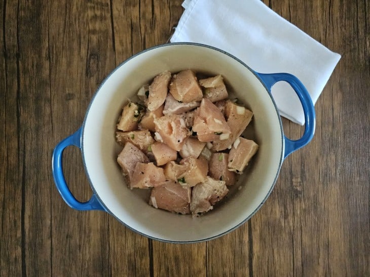 Uma panela contendo pedaços de frango sendo fritos.