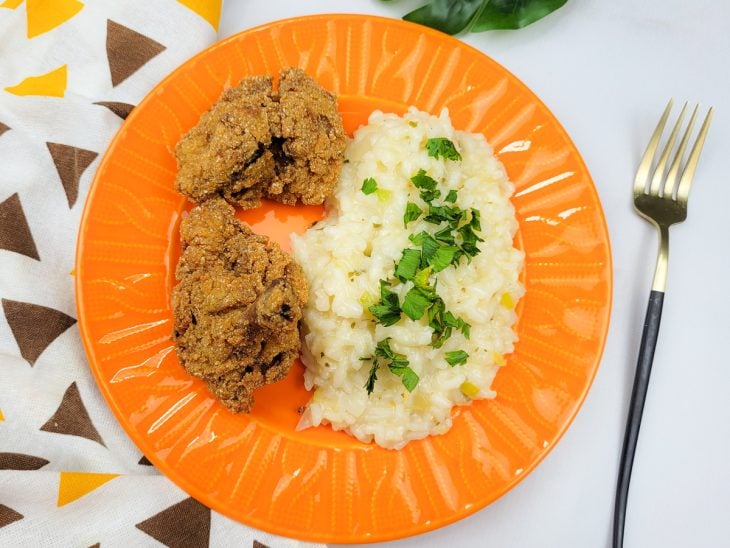 Coxinhas servidas com arroz cremoso ao lado no prato.