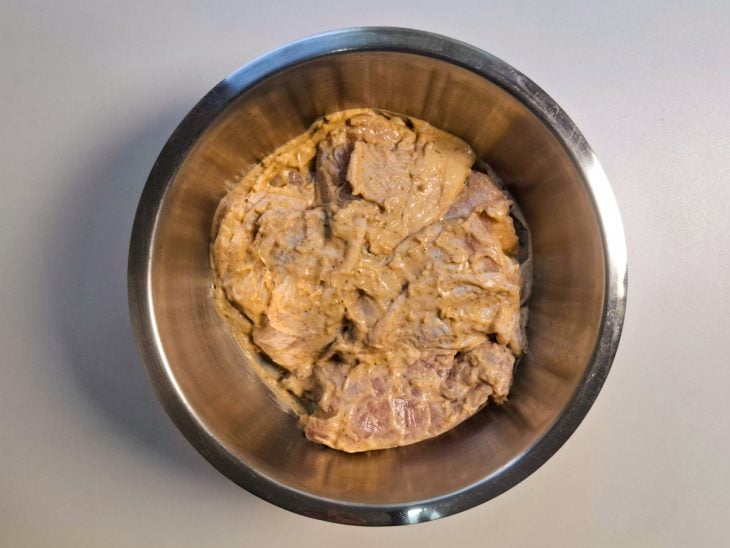 Frango com temperos em uma tigela de inox redonda.