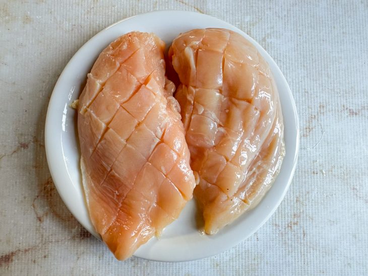 Peitos de frango com cortes superficiais feitos na superfície.