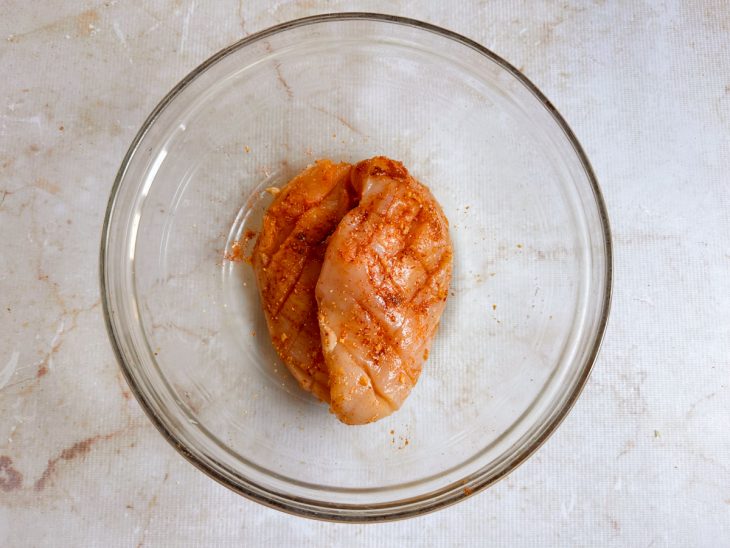 Frango temperado com especiarias espalhadas inclusive nos cortes.