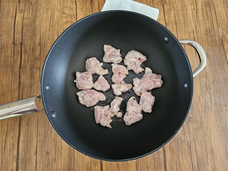 Pedaços de frango empanados e colocados na frigideira.