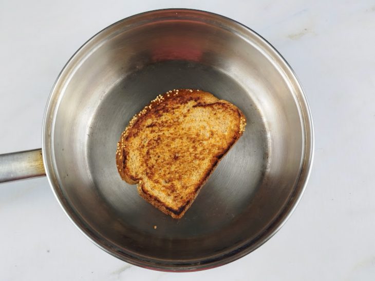 Fatia de pão grelhada em uma frigideira com manteiga.