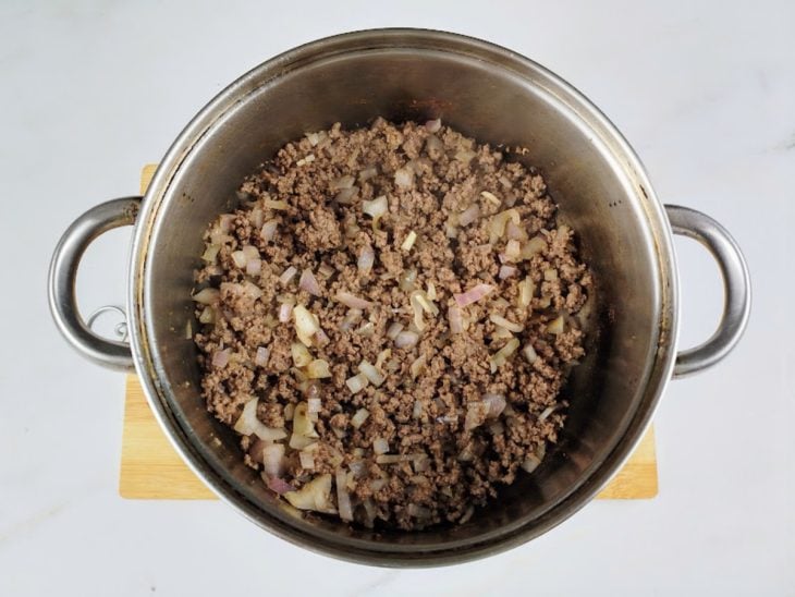 Uma panela com carne moída, alho, cebola e temperos.