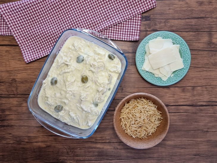 Refratário com frango cremoso e recipientes com mussarela e batata palha separados.