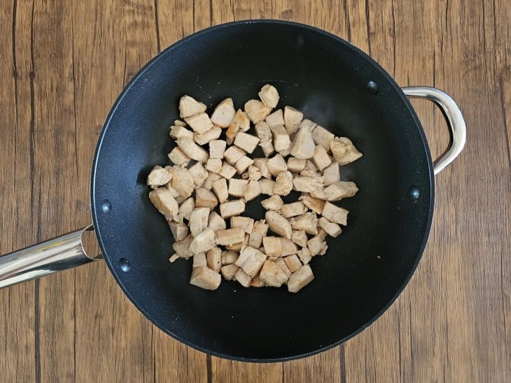 Um frigideira com cubos de frango refogados.