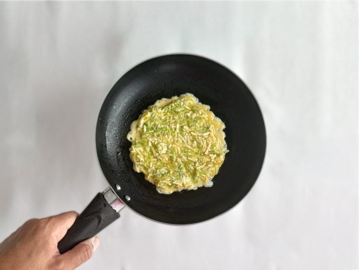 Uma frigideira com óleo e uma porção da massa.