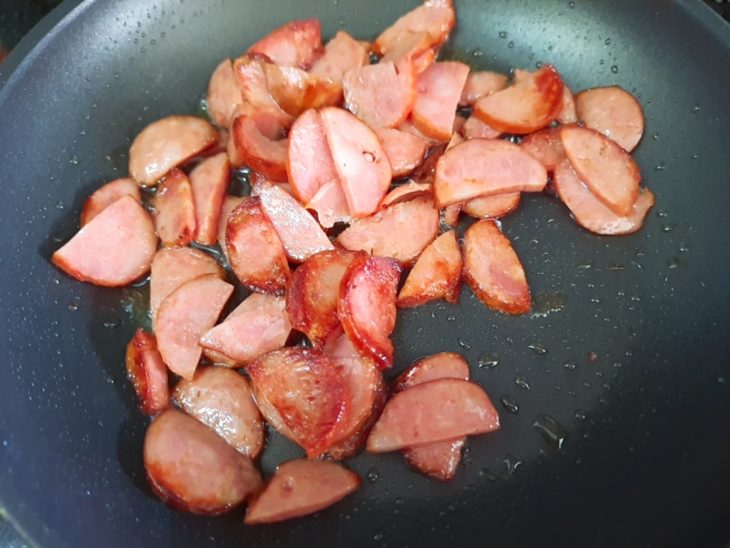 Uma frigideira com a calabresa a dourar.