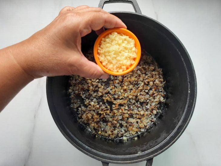 Uma panela com alho e cebola picados a dourar.