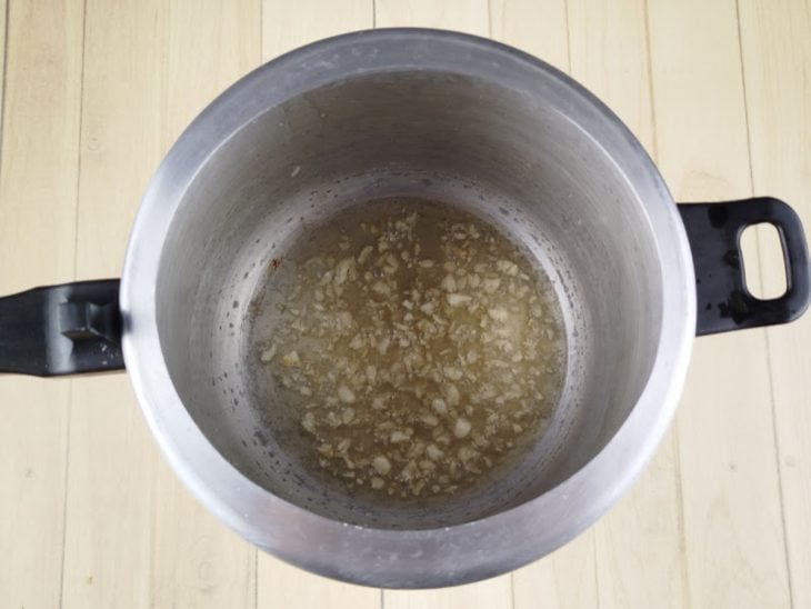 Na panela de pressão, alho fritando na banha de porco.
