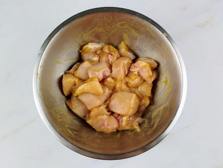 Cubos de frango temperados em uma tigela redonda de inox.