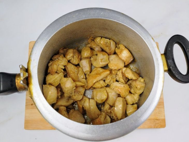 Cubos de frango dourados na panela de pressão.