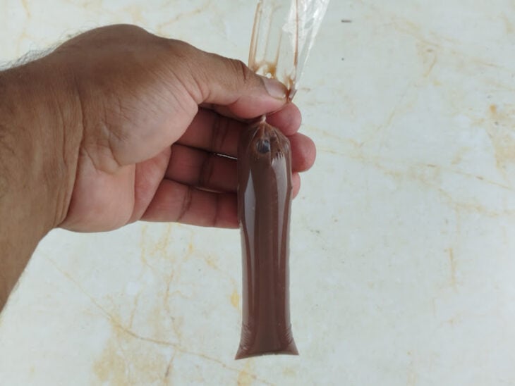 Base de chocolate sendo despejada no saquinho até atingir a quantidade desejada.