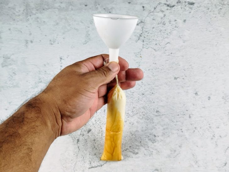 Funil na ponta de um saquinho preenchido com o líquido do geladinho.