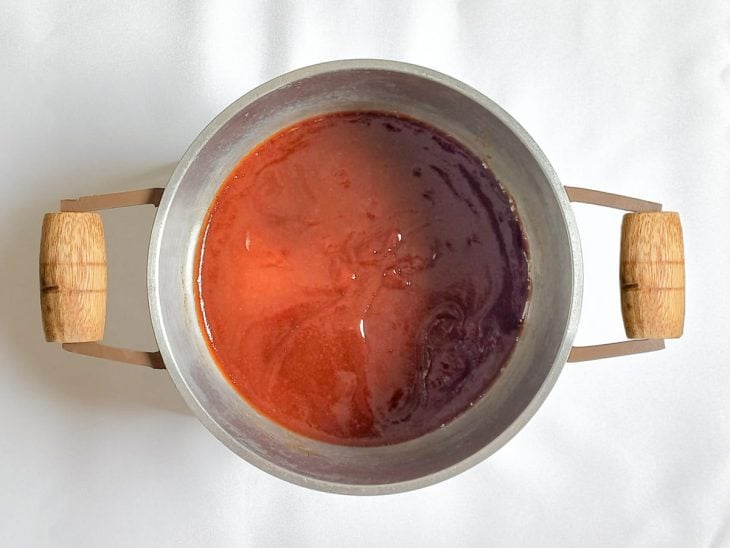 Panela com goiabada em pedaços derretida em água.