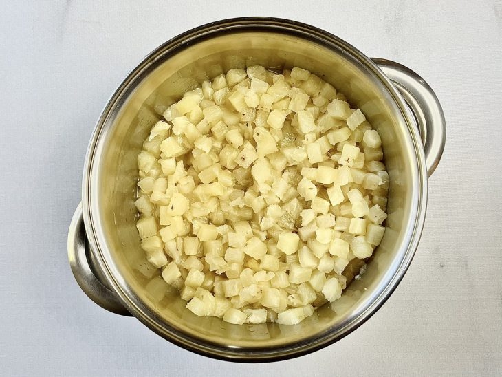 Abacaxi cozinhando em uma panela com água e açúcar.