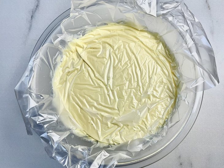 Creme reservado em uma tigela de vidro coberta com plástico-filme.