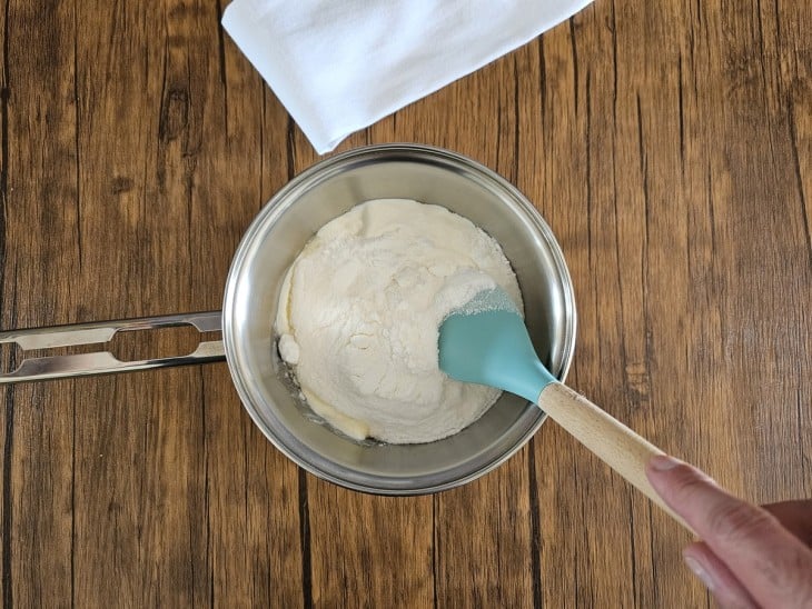 Uma panela com a mistura de creme de leite, leite de coco em pó e açúcar.