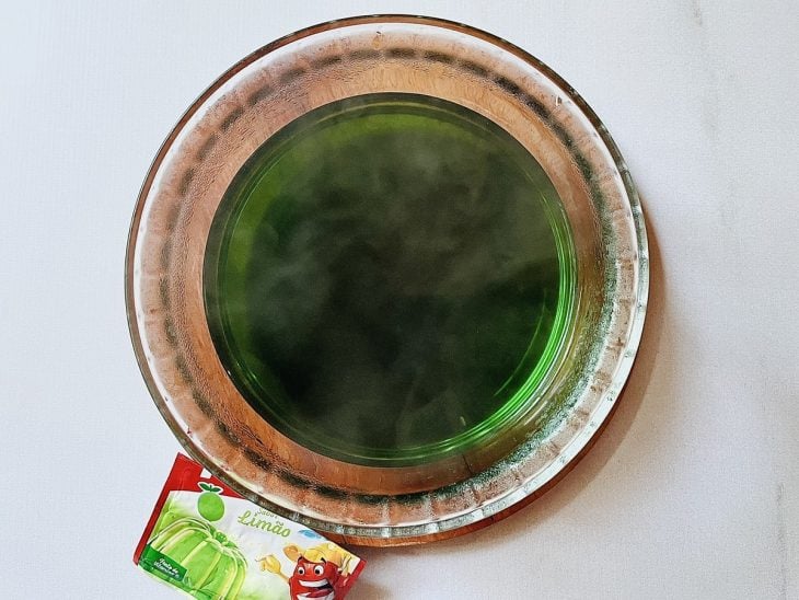 Pó de gelatina de limão dissolvida em água em uma tigela de vidro.