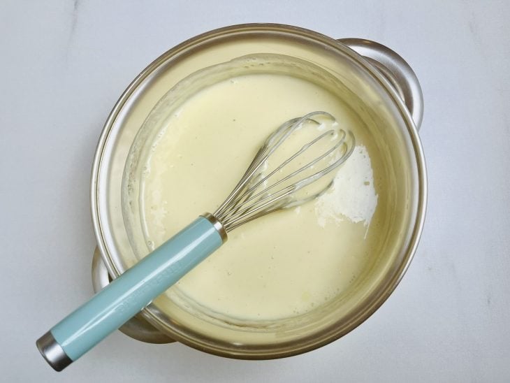 Mistura de creme de leite, leite condensado e leite em pó cozinhando na panela.