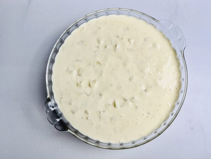 Creme misturado com os pedaços de abacaxi em um refratário de vidro.