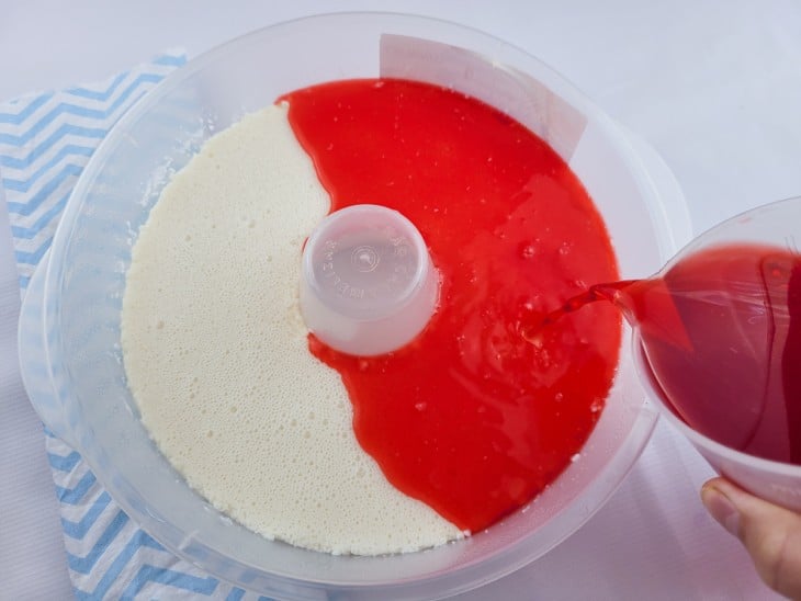Uma forma redonda, com furo no meio contendo creme branco e gelatina de morango por cima.