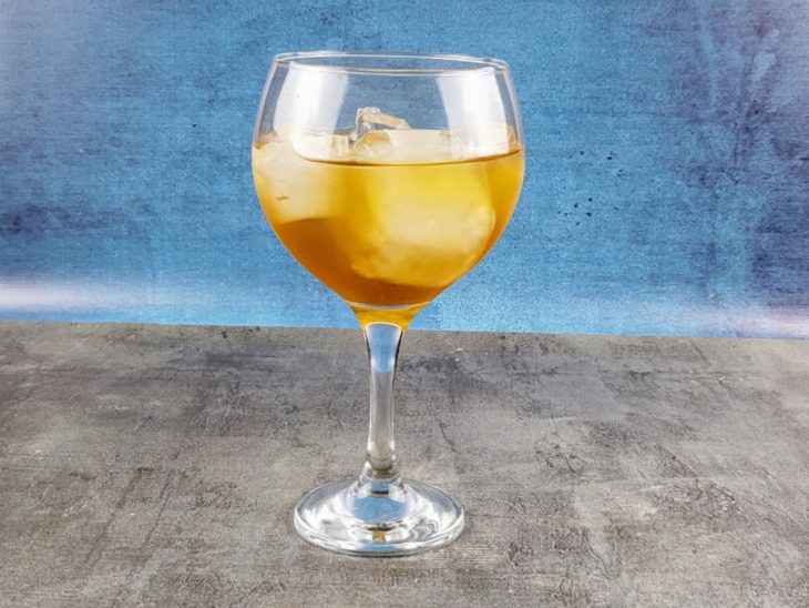 Gelo, gin e chá misturados em uma taça.