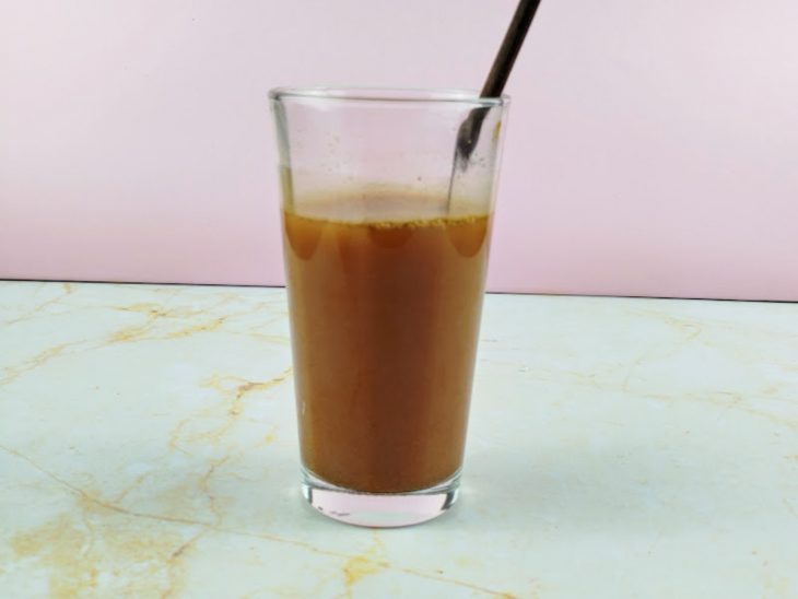 Copo com ingredientes misturados e colher apoiada.