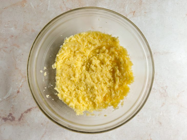 Batatas ainda quentes sendo descascadas e amassadas.