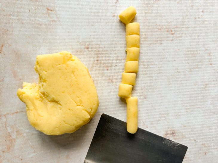 Porções da massa sendo enroladas em formato de rolinho.