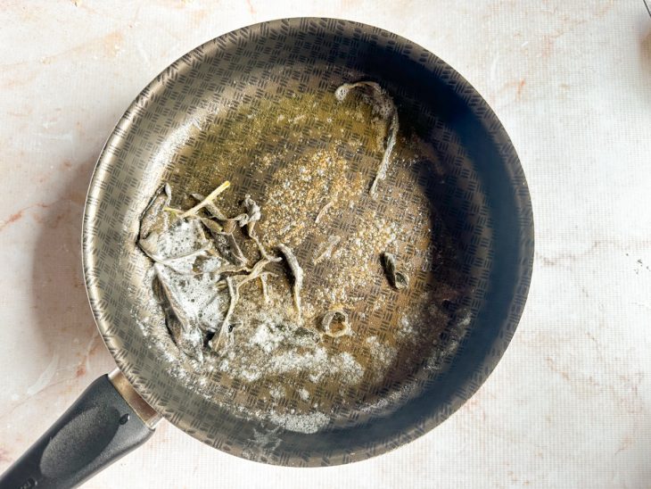 Manteiga dourando com folhas de sálvia na panela.