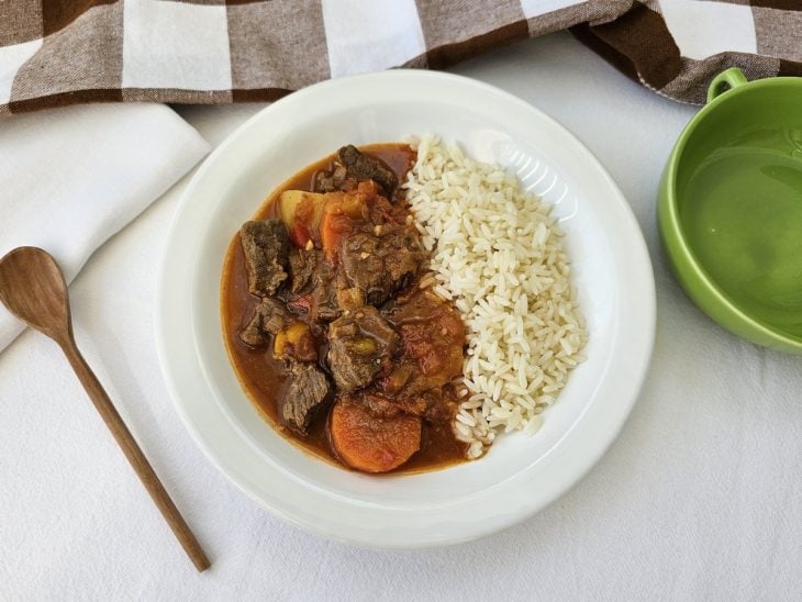 Porção de Goulash em um prato servido com arroz branco.