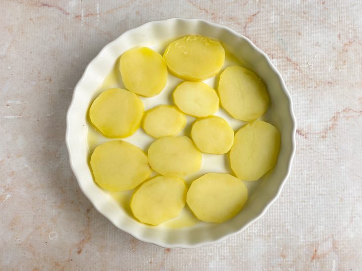 Refratário redondo forrado com rodelas de batatas cozidas.