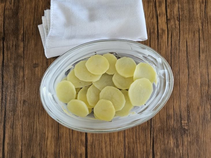 Um refratário forrando com rodelas de batata.