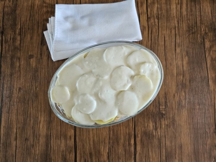 Um refratário contendo batatas cobertas com creme branco.