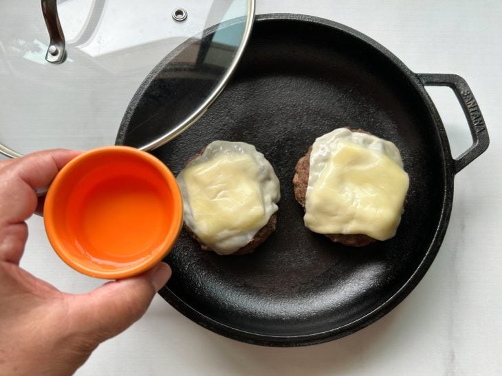 Hambúrguer com fatia de queijo na frigideira.