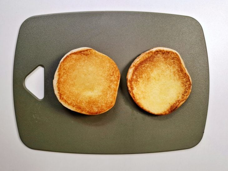 Pão brioche cortado ao meio e selado com manteiga.
