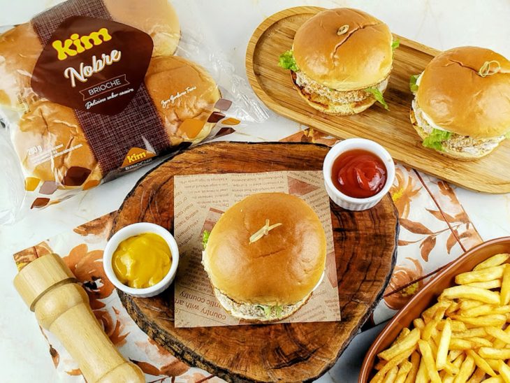 Hambúrgueres prontos, servidos em tábua com molhos.