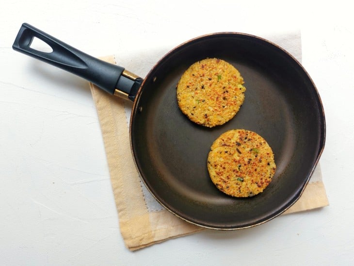 Uma frigideira com dois hambúrgueres de quinoa.