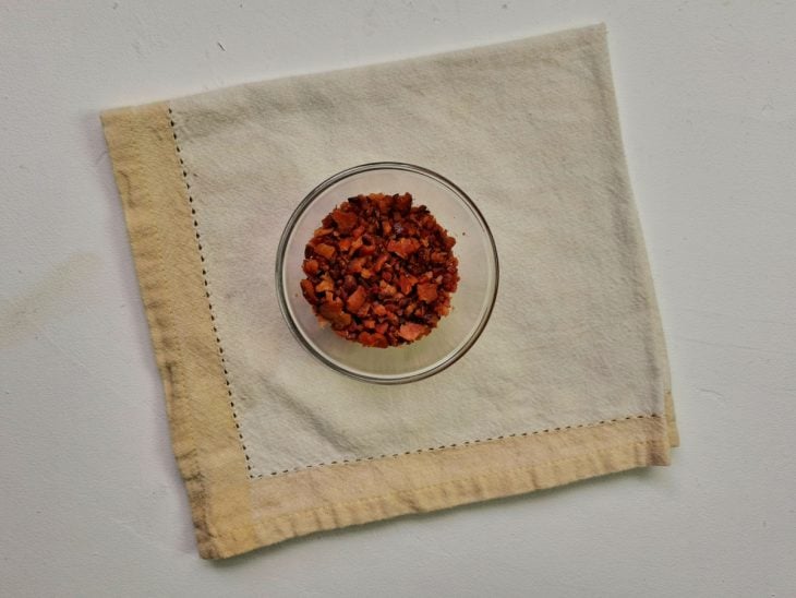 Um recipiente contendo cubinhos de bacons fritos.