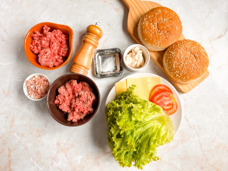 Ingredientes organizados na bancada, com pães, carnes e vegetais visíveis.